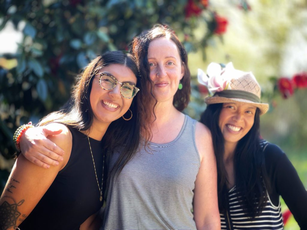 Three women in a garden smiling to the camera