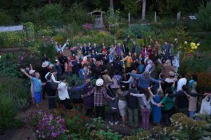 Hollyhock´s staff and students together in the garden celebrating and raising hands.