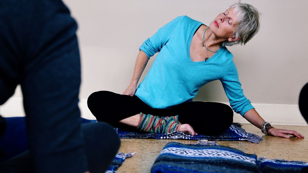 Anne Pitman demonstrating a yoga pose during Informed by Cancer, at Hollyhock from August 30 - September 3.